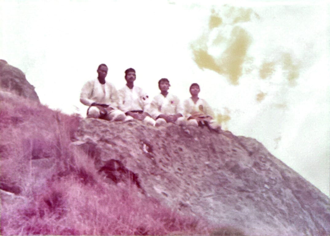 Four S.A. Budo Ryu karate students in white gi seated on a hillside in KwaZulu-Natal, archive photograph